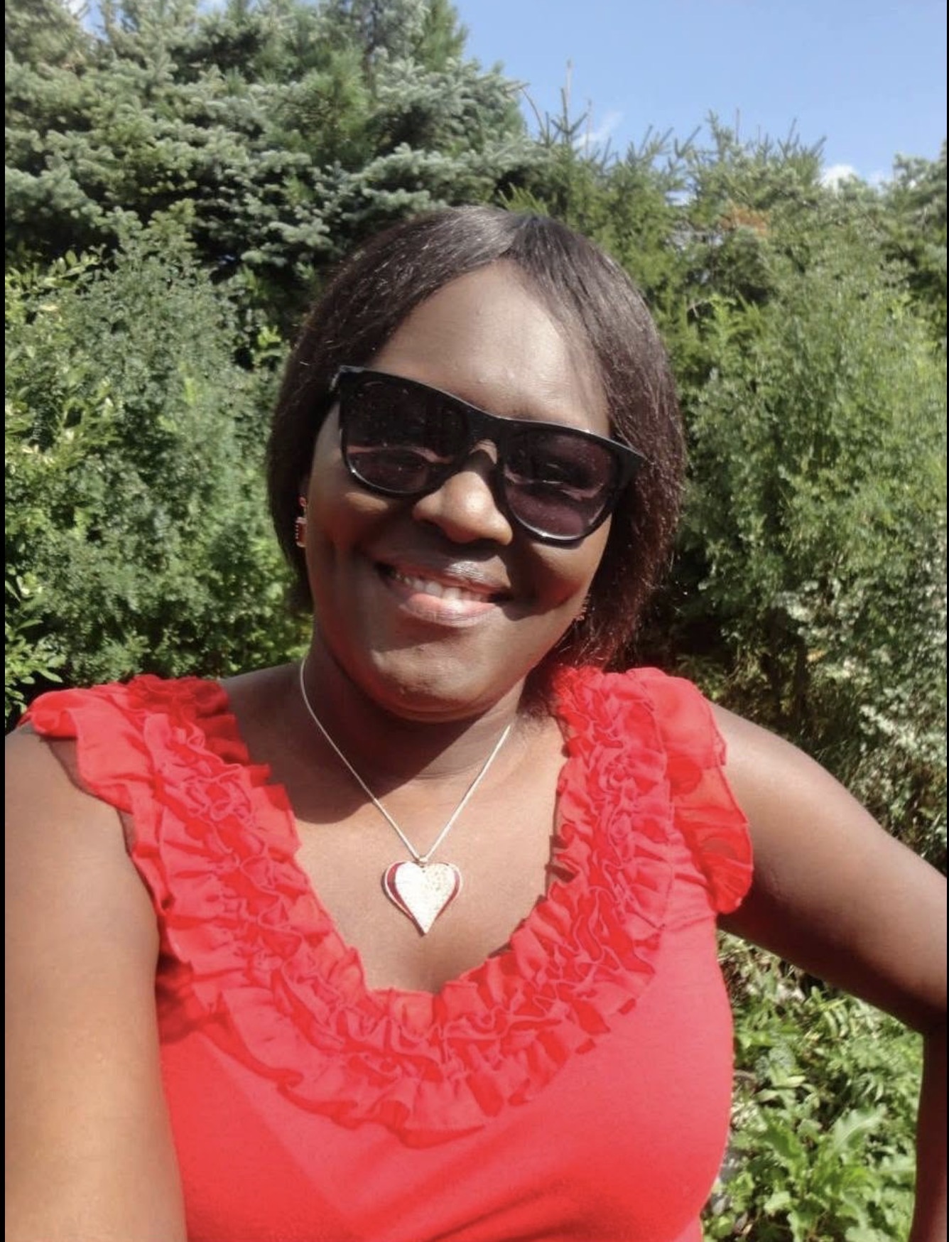 Susan Andrua Wilson smiling in a red dress on a summer day, 2014